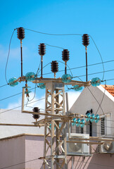electric pole with transformer and wires against the background of the building and the blue sky