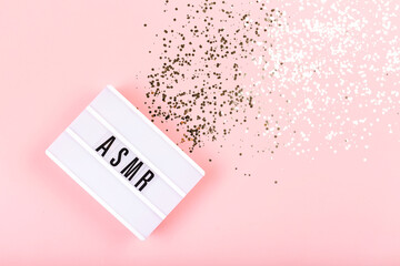 The lamp with letters ASMR on pink background. Decorated with confetti. Sound and visual practice for anxiety, stress and panic relief.  Flat-lay.