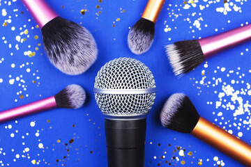 A microphone with many brushes decorated with confetti on blue background. ASMR or preparing for the stage concept. Sound and visual practice for anxiety, stress and panic relief.  Flat-lay.