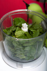 Spinach and mint in a blender bowl for chopping. For making biscuit roll with spinach and mint. Stuffed with strawberries. Ingredients for cooking.