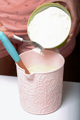 A woman adds flour to the dough. For the preparation of biscuit roll with spinach and mint. Stuffed with strawberries. Ingredients for cooking.