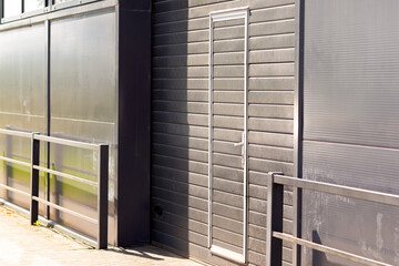 Details of gray facade with windows on industrial building reflect clouds on windows