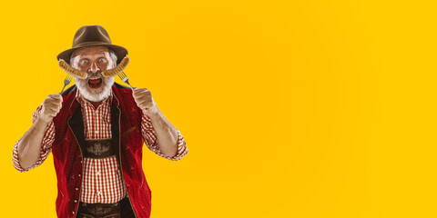 Delighted men with sausages dressed in traditional Austrian or Bavarian costume holding mug of beer at pub or studio. The celebration, oktoberfest, festival, drinking concept. Flyer with copyspace.