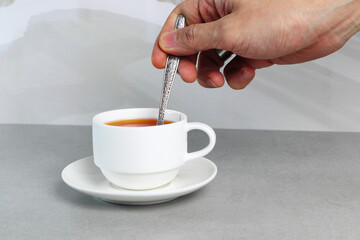 a right hand stir a cup of coffee on the grey table in the morning