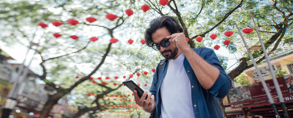 A man got lost on a Chinese street and looks at the map on the phone