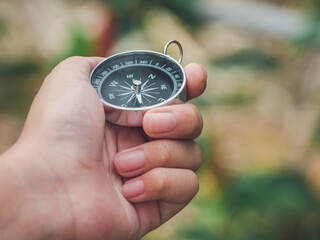Hand of child hand using magnetic golden compass while traveling in the jungle or forest and...