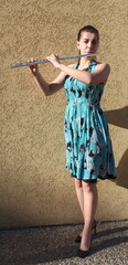 Girl plays the flute in front of a brown background