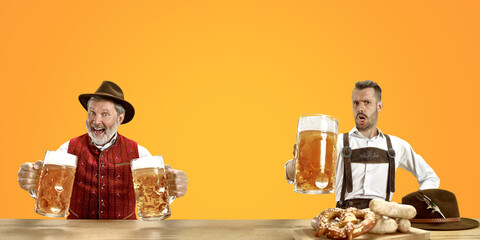 Delighted men with beer dressed in traditional Austrian or Bavarian costume holding mug of beer at pub or studio. The celebration, oktoberfest, festival, drinking concept. Flyer with copyspace.