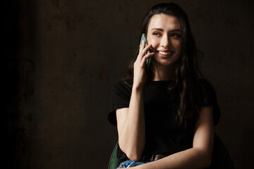 Photo of beautiful woman sitting on chair and talking on cellphone
