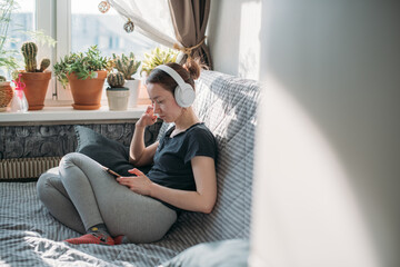 Fototapeta premium Girl sitting on a sofa with a phone in her hands