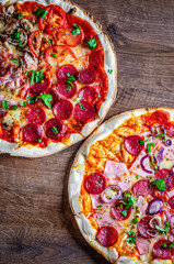 pepperoni pizza and Pizza "Four Seasons" with Mozzarella cheese, ham, tomato sauce, salami, bacon, mushroom, pepper, Spices and Fresh basil. two Italian pizza on wooden table background
