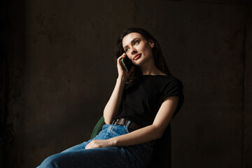 Photo of beautiful woman sitting on chair and talking on cellphone