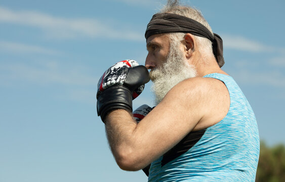 Healthy Fighter Bearded Senior Old Man Boxing Gloves. Boxer With Boxing Glove. Handsome Mature Man Practicing Boxing Kicks.