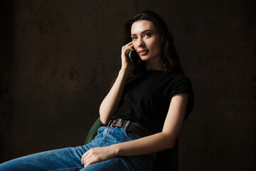 Photo of beautiful woman sitting on chair and talking on cellphone