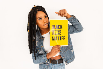 Young beautiful woman with dreadlocks in blue jeans clothes protests and holds a yellow poster...