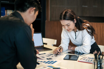 Fototapeta premium Two young asian modern people planning work together as a team and present ideas at work. Creative business team sitting working together at office.