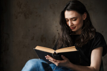 Photo of beautiful young woman sitting on chair and reading book