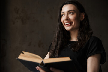 Photo of beautiful young brunette woman smiling and reading book