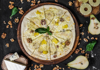 Cheese pizza with pear and nuts on a dark background