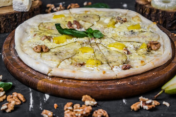 Cheese pizza with pear and nuts on a dark background