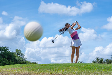 Golf ball just coming off the tee from girl golfer in swing in the morning time.
