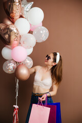 Smiling happy brunette fashionable woman holding balloons posing. Studio shot.