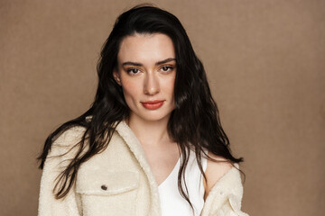 Photo of seductive young woman in jacket posing and looking at camera