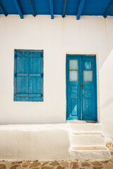Traditional Greek house with blue window and whitewashed wall in Milos Island in the Cyclades in Greece