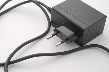An AC adapter with some dust on it laying on a table.