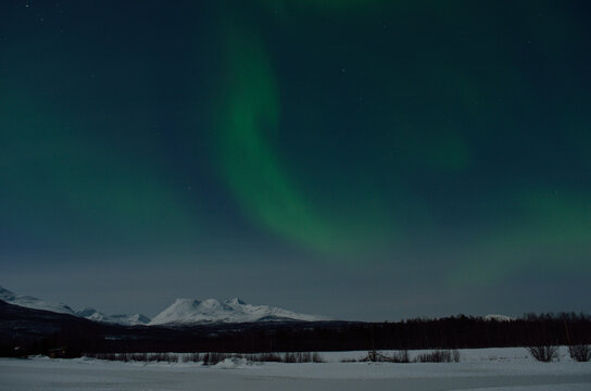 aurora borealis, northern light over winter landscape and snowy mountain