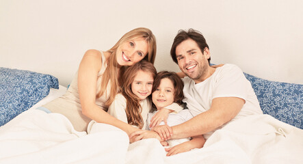 Fototapeta premium Happy family with two kids in bed