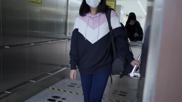 Asian woman wear mask using elevator at airport terminal, going up stairs, covid-19 pandemic, new normal social distancing, female in mask walking into lift elevator, public surface contamination
