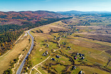 Panoramic aerial view of the mountain highway and village in spring. Beautiful skyview countryside landscape. Carpathian mountains. Ukraine