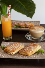 Roll pancakes or crepes, syrniki, cappuccino and orange juice. Traditional Russian breakfast