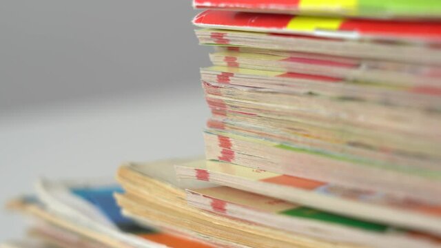 Closeup up view 4k video footage of stack of many old paper magazines isolated on table. Shallow depth of field.