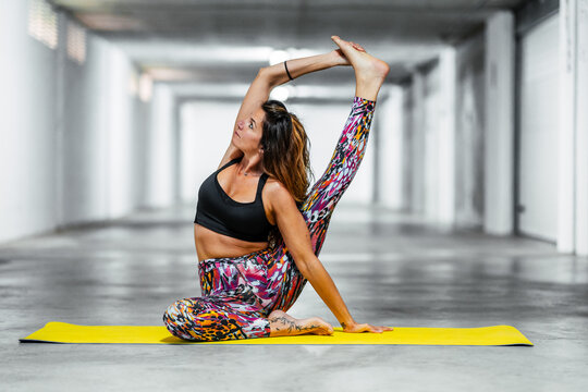 Full Body Young Flexible Female In Active Wear Sitting In Compass Pose And Stretching Muscles While Practicing Yoga In Garage Hall