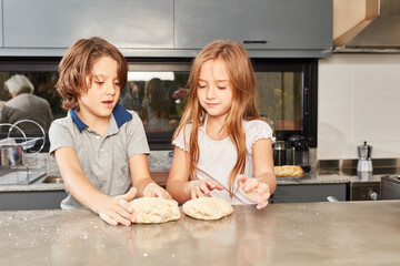 Obraz na płótnie Canvas Two sibling kids knead dough together