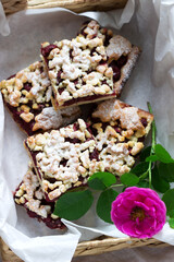 Sweet cake with cherry rose arenas and streusel on a wooden background. Rustic style.