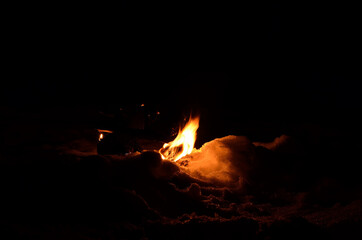 birch log fire on snow at night