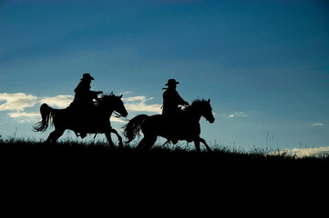 Cowboy silhouette horses galloping