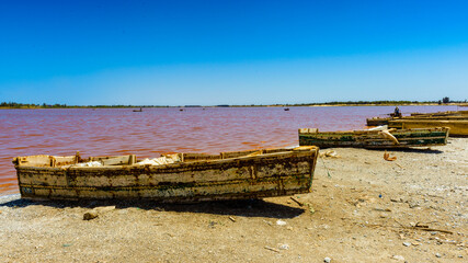 It's Coast of a pink water lake in Senegal with boat on it