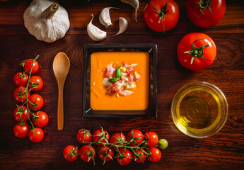 Receta típica española de salmorejo cordobés en un plato cuadrado y con algunos ingredientes al rededor.