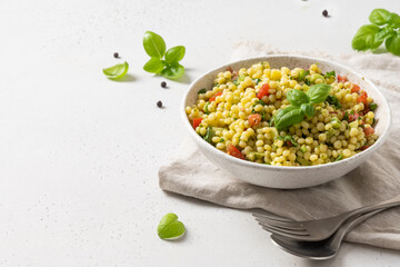 Pasta ptitim with vegetables on white. Close up. Copy space.