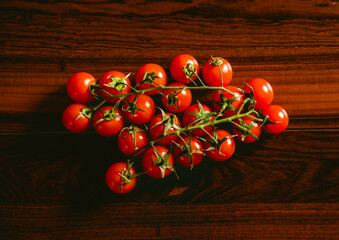 Fototapeta na wymiar Tomates cherry sobre una mesa de madera marrón oscuro.
