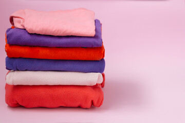 stack of folded clothes or towels on a pink background