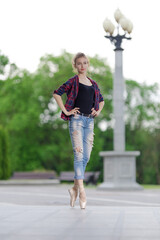 Girl ballerina in jeans, a plaid shirt and pointe shoes dancing in the city on the street © Tatiana