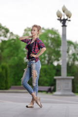 Girl ballerina in jeans, a plaid shirt and pointe shoes dancing in the city on the street © Tatiana