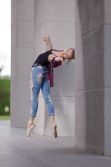 Girl ballerina in jeans, a plaid shirt and pointe shoes dancing in the city on the street © Tatiana