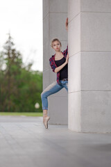 Girl ballerina in jeans, a plaid shirt and pointe shoes dancing in the city on the street © Tatiana