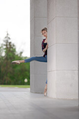 Girl ballerina in jeans, a plaid shirt and pointe shoes dancing in the city on the street © Tatiana